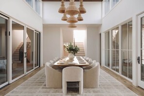 A modern dining room with a long table, cushioned chairs, and a hanging light fixture. - Lakefront Retreat | The Lucas (Eufaula)