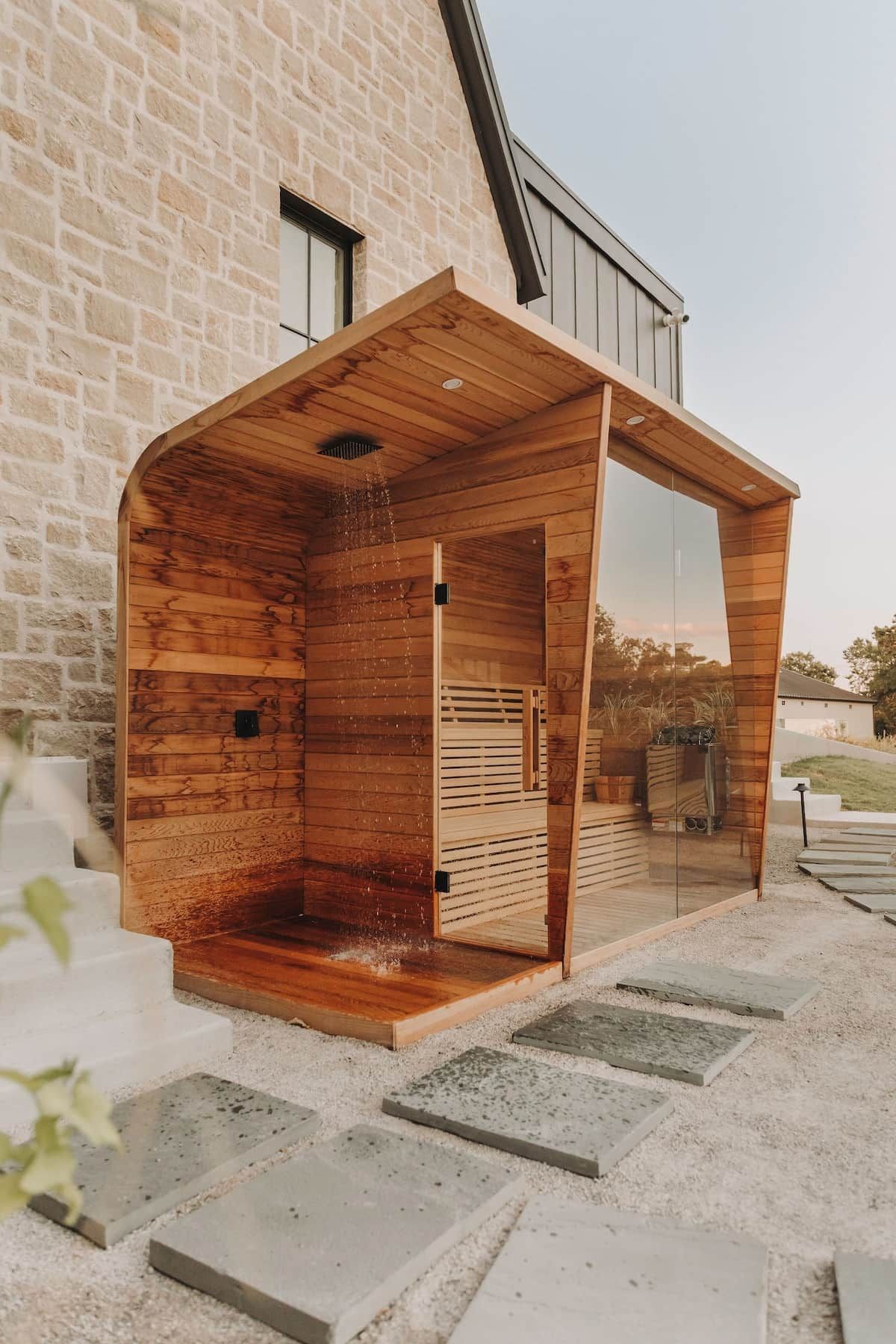 Una sauna de fusta amb una porta de vidre, davant d'un edifici de pedra.