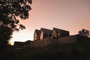 A large, multi-story building with a prominent central section and smaller wings, surrounded by a concrete wall. - Lakefront Retreat | The Lucas (Eufaula)