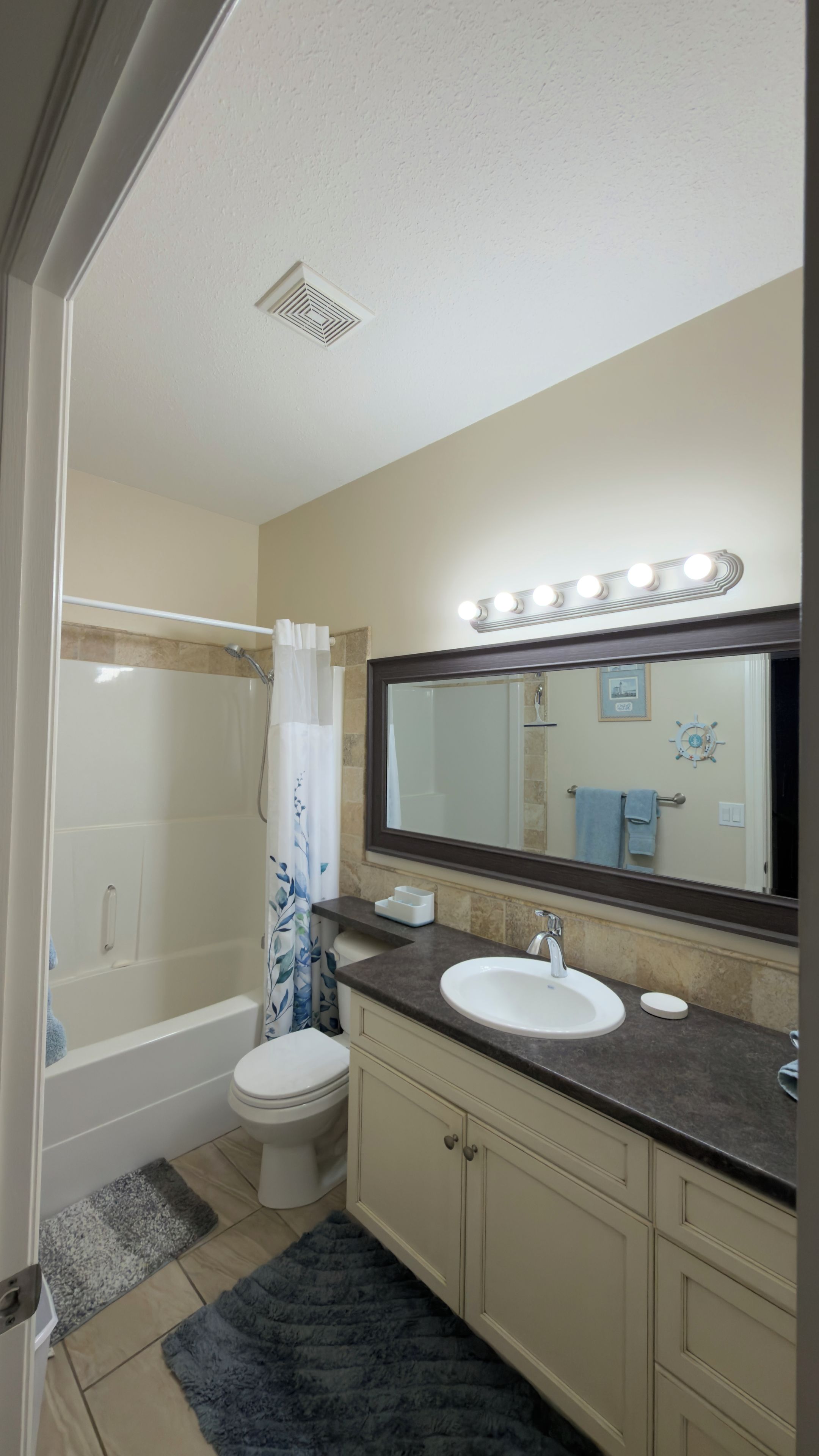 Un baño con bañera, inodoro, lavamanos y espejo con iluminación.