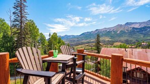 A wooden deck with Adirondack chairs and a table, overlooking a mountainous landscape with houses in the valley. - 115 Tristant by Avantstay Hot Tub + Gym + Ridge Views Ski-in/out Funicular + Gondola (Telluride)