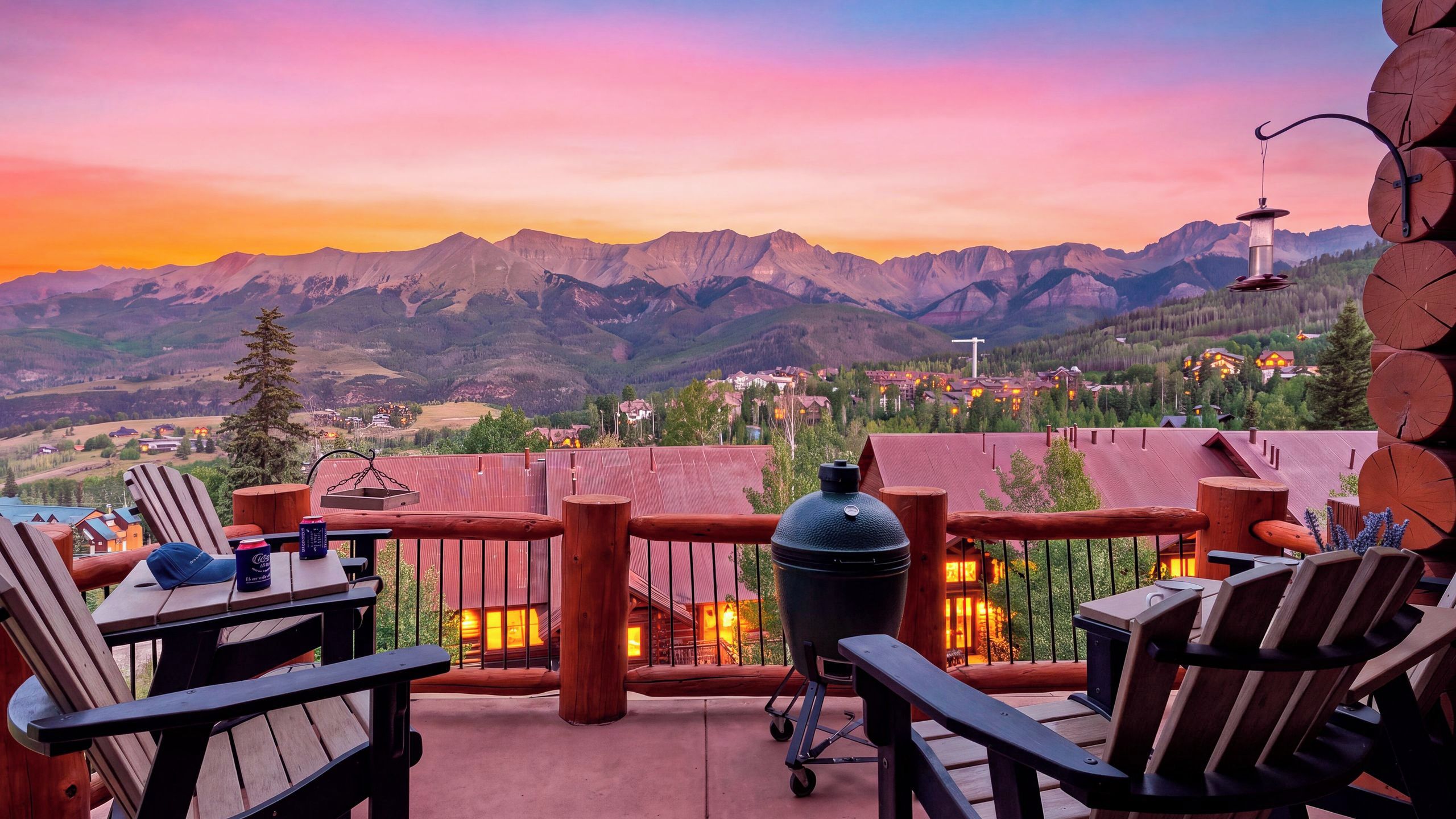 A patio with outdoor seating, a grill, and a view of mountains at sunset.