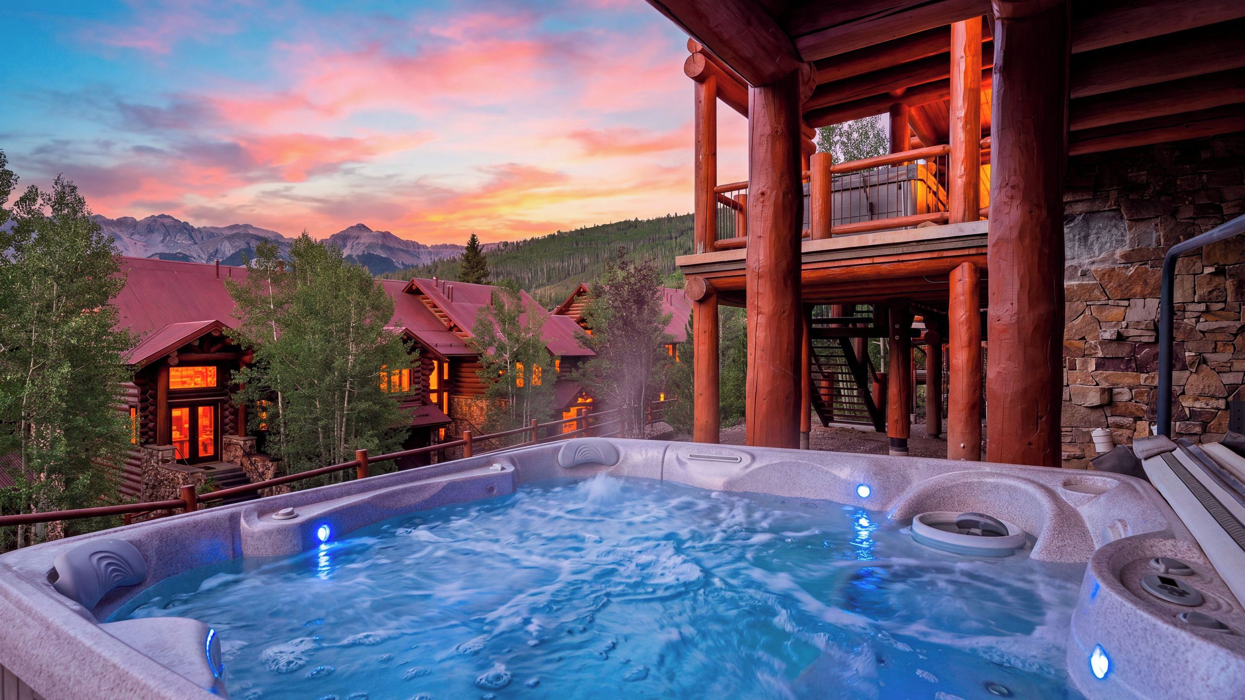 A hot tub with a view of mountains and a wooden cabin.