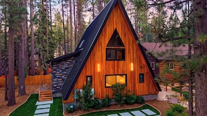 A cabin with a triangular roof, wooden siding, and a small porch with steps. - The Blackwood A-frame by Avantstay Hot Tub & Pond Arcade Room EV Charger Near Slopes & Lake (Big Bear Lake)