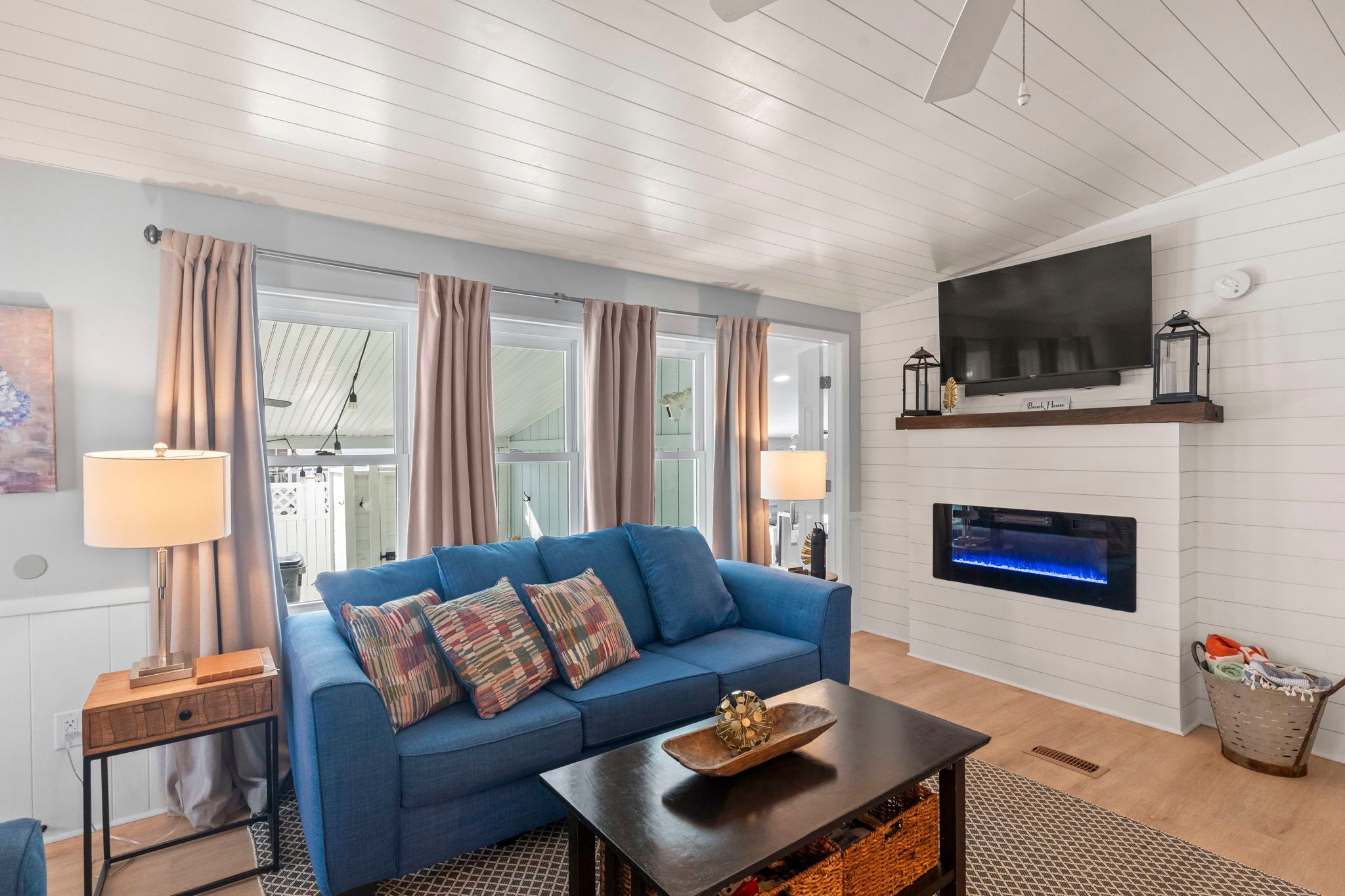 A living room with a blue sofa, two lamps, a flat-screen TV, and a fireplace.