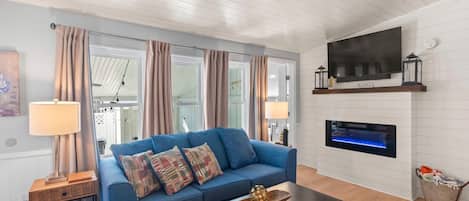 A living room with a blue sofa, two lamps, a flat-screen TV, and a fireplace.