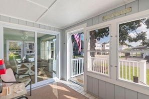 A covered outdoor area with a sliding glass door leading to a patio with furniture. - Grace Cottage, Your Perfect Surfside Beach Getaway (Surfside Beach)