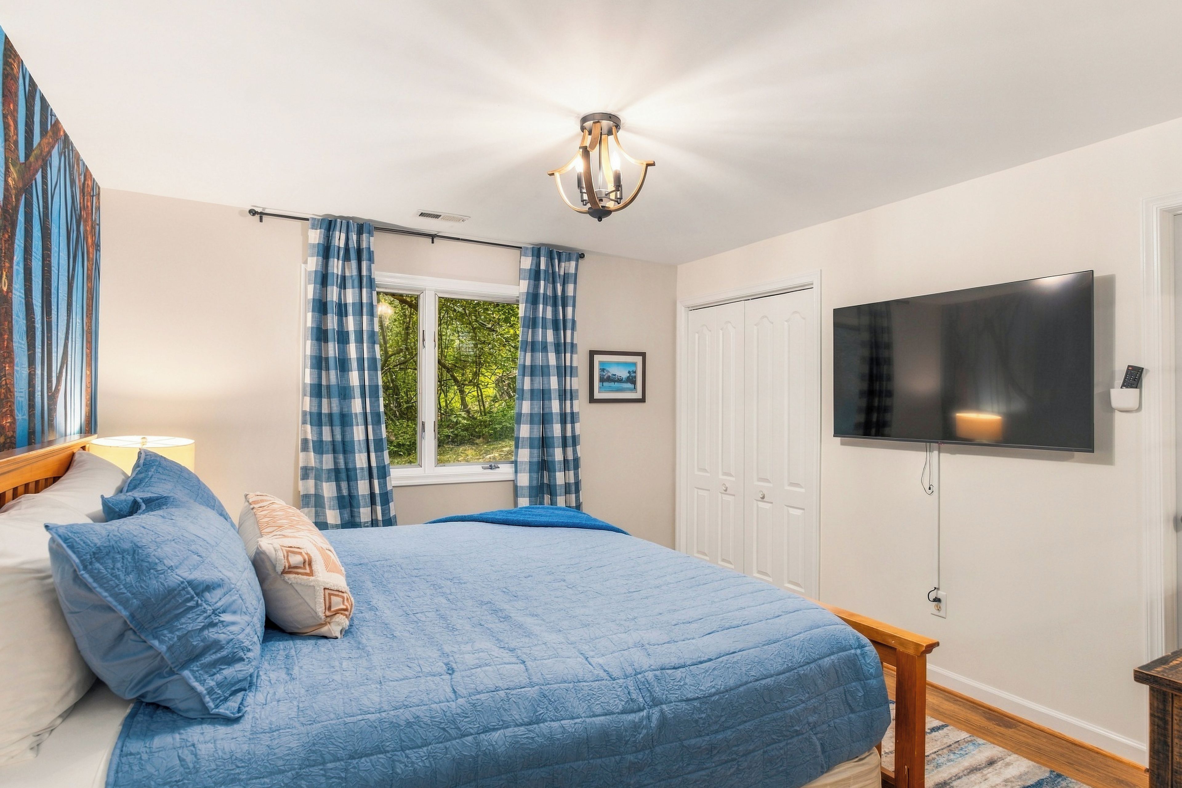 Un dormitorio con cama, cortinas, ventana, televisor y puerta.