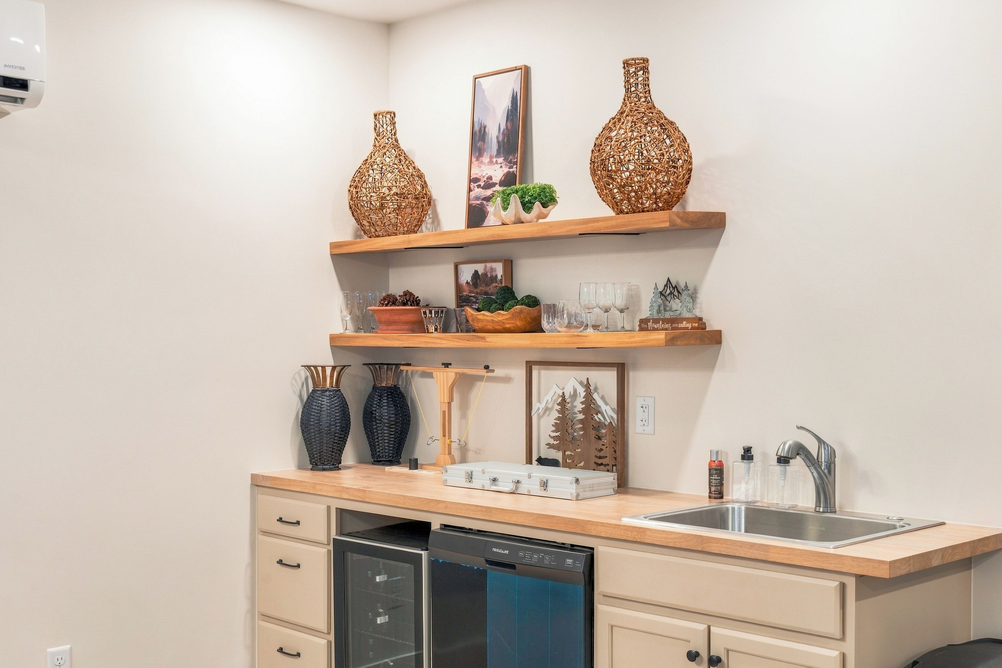 A kitchen with a dishwasher, a sink, and decorative items on shelves.