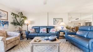 Ein Wohnzimmer mit einem blauen Ledersofa, einem gemusterten Sessel, einem Couchtisch und einer Stehlampe.
