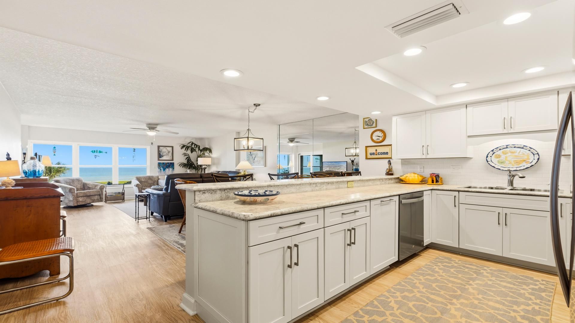 A spacious kitchen with a large island, white cabinetry, and a view to the outside.