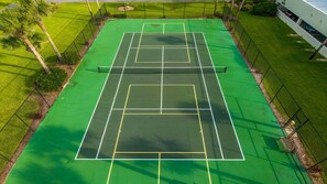 An outdoor tennis court with a net, surrounded by a fence and greenery. - Oceanfront Crescent Beach • 3 King Beds • Private Terrace • Pool (Saint Augustine)