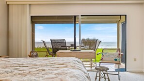 A hotel room with a bed, a table with chairs, and a view of the ocean through a sliding glass door. - Oceanfront Crescent Beach • 3 King Beds • Private Terrace • Pool (Saint Augustine)