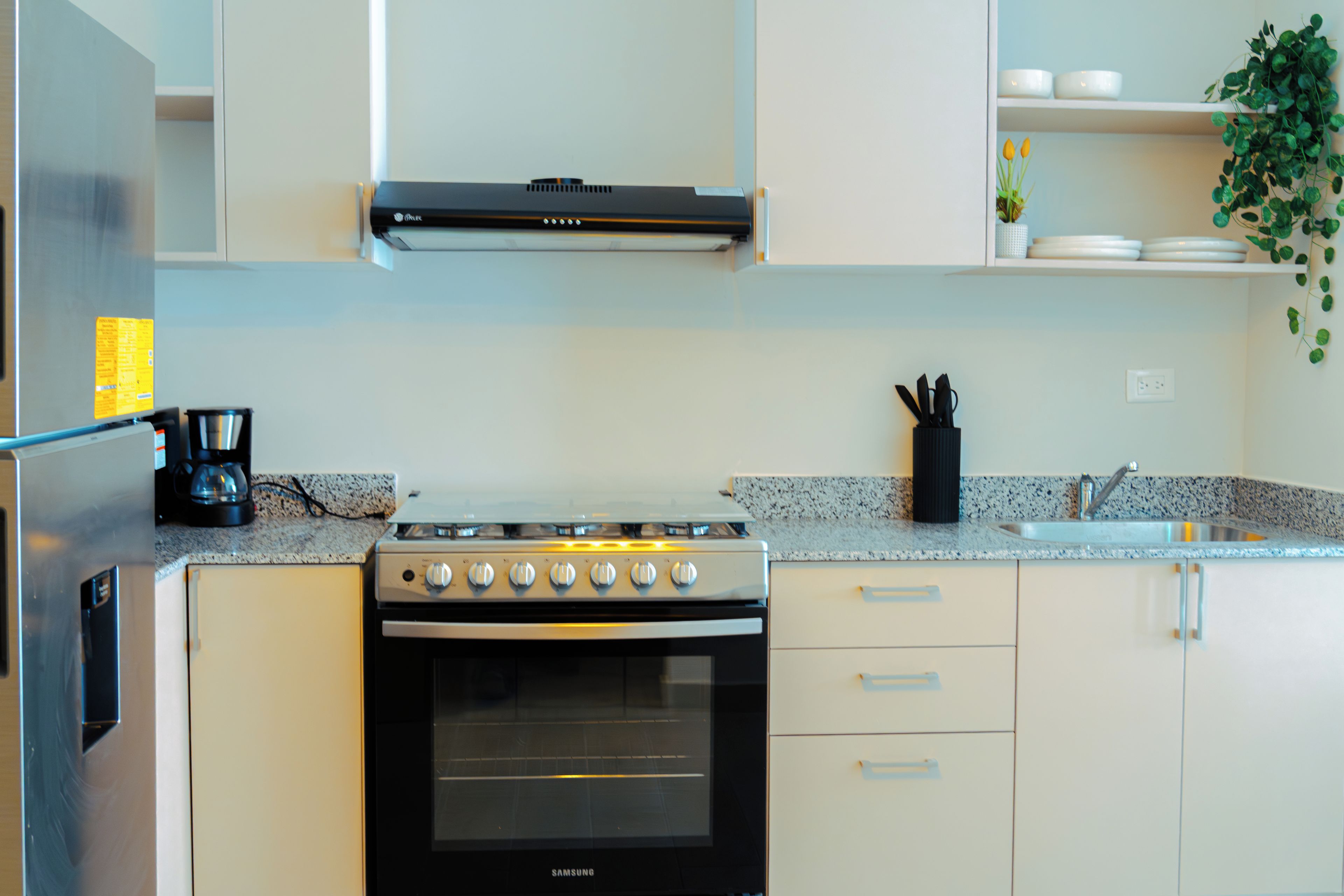 A modern kitchen with a built-in oven, stainless steel appliances, and white cabinetry.