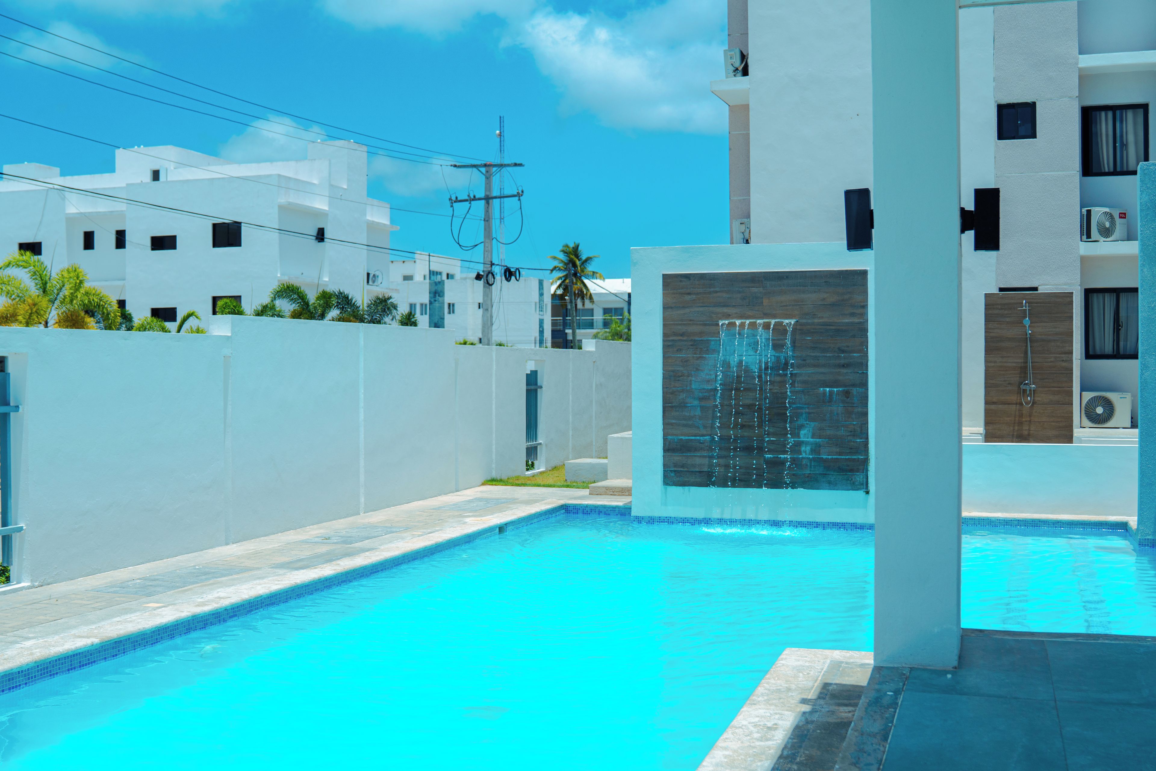 Una piscina con fuente, rodeada por un edificio blanco con múltiples ventanas y balcones.
