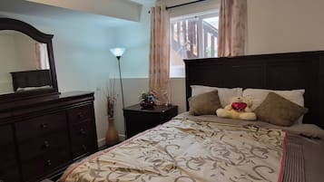 Un dormitorio con cama, cómoda, mesita de noche, lámpara y ventana con cortinas.