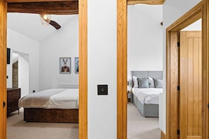 A bedroom with a bed, a bedside table, and a nightstand. There is a wooden door frame and a white wall. - Spacious Luxury Barn| Countryside Stay in Newburgh (Wigan)