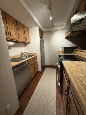 A kitchen with wooden cabinets, a stainless steel refrigerator, a black stove, and a dishwasher. - Mountain Views - Third floor 2 bdrm loft condo in Frisco, walk to town! (Breckenridge)