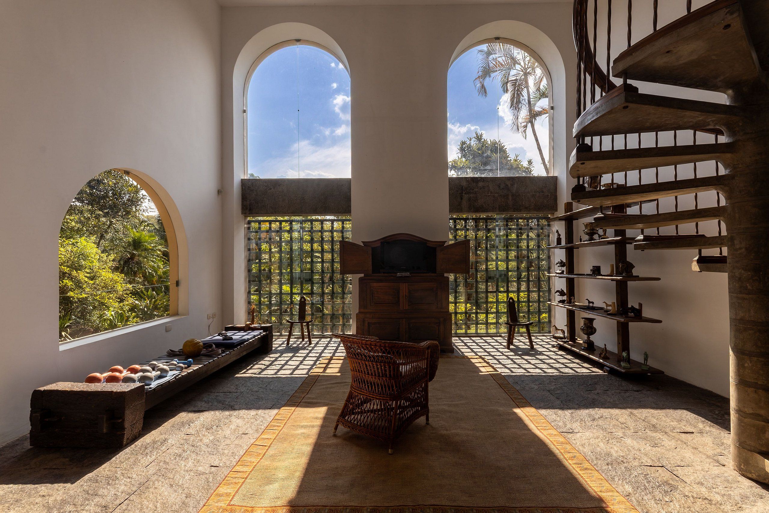 A room with a central seating area, a fireplace, and a view through a window with a metal gate.