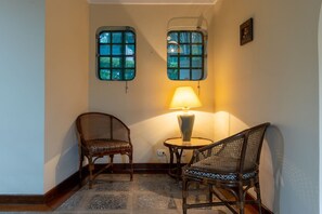 A room with two wicker chairs, a small round table, and two windows with a view of greenery. - 5 QTS Fut Tenis Sauna Boate 30min SP (Carapicuíba)