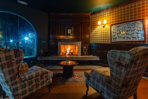 A cozy room with a fireplace, two armchairs, and a large window. - 5 QTS Fut Tenis Sauna Boate 30min SP (Carapicuíba)