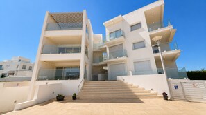 A multi-story residential building with balconies, a staircase, and a gated entrance. - Trident Luxury Beach Apt by TrulyCyprus (Paralimni)