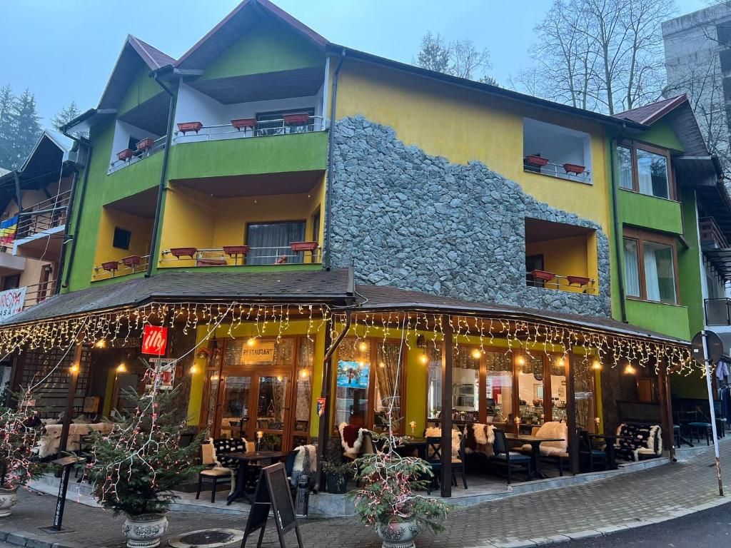 A two-story building with a restaurant on the ground floor, outdoor seating, and a stone facade.