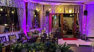 A dining area with tables set for a meal, featuring a red carpet leading to a doorway.