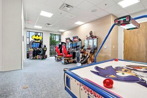 A room with a pool table, arcade games, and a large window. - 10BR Luxury Villa, Pool & Hot Tub, Windsor Cay (Clermont)