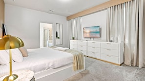 Un dormitorio con cama, mesita de noche, televisor y cómoda.