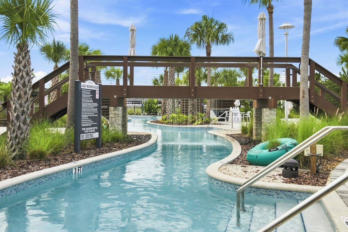 A swimming pool with a bridge, palm trees, and a sign indicating no diving.