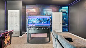 A room with a foosball table, a door, and a wall with a blue illuminated circuit board design. - 10BR Luxury Villa, Pool & Hot Tub, Windsor Cay (Clermont)