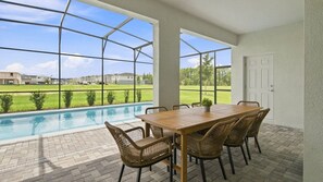 A covered patio with a pool, outdoor table, and chairs. - 10BR Luxury Villa, Pool & Hot Tub, Windsor Cay (Clermont)