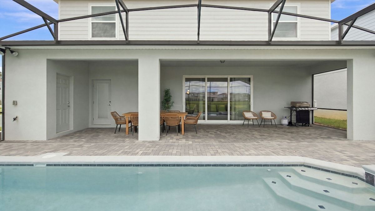 Un patio techado con piscina, mobiliario exterior y una parrilla.