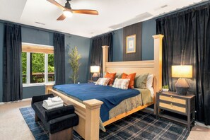 Ein Schlafzimmer mit einem großen Bett, zwei Nachttischen mit Lampen, einem Deckenventilator und einem Fenster mit Vorhängen.