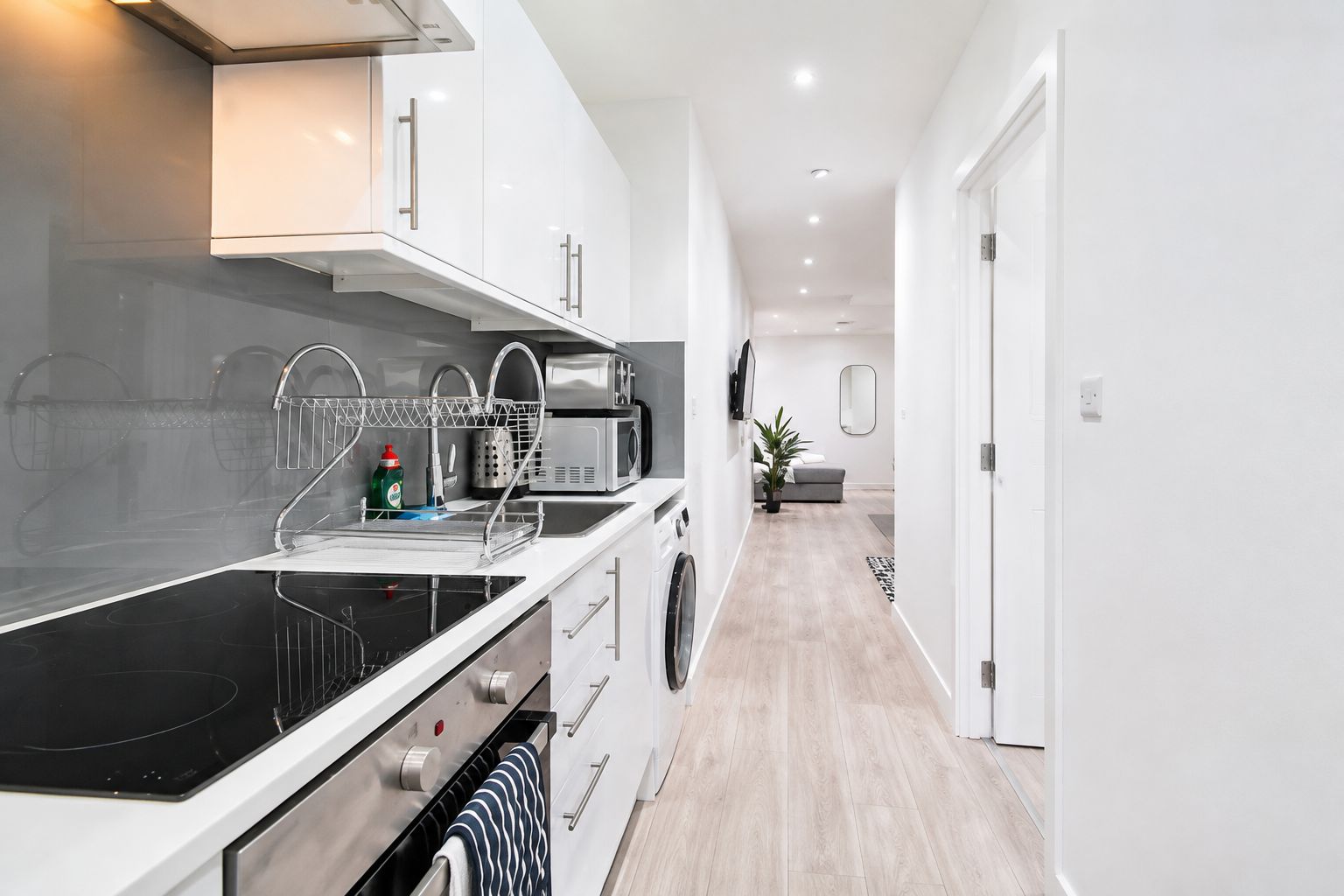 A modern kitchen with a black stovetop, stainless steel appliances, and a white countertop.