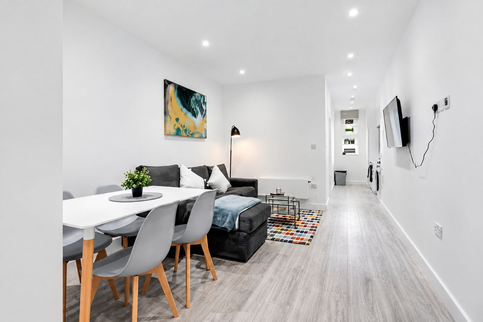 A modern living room with a dining area, a sofa, a coffee table, and a painting on the wall.