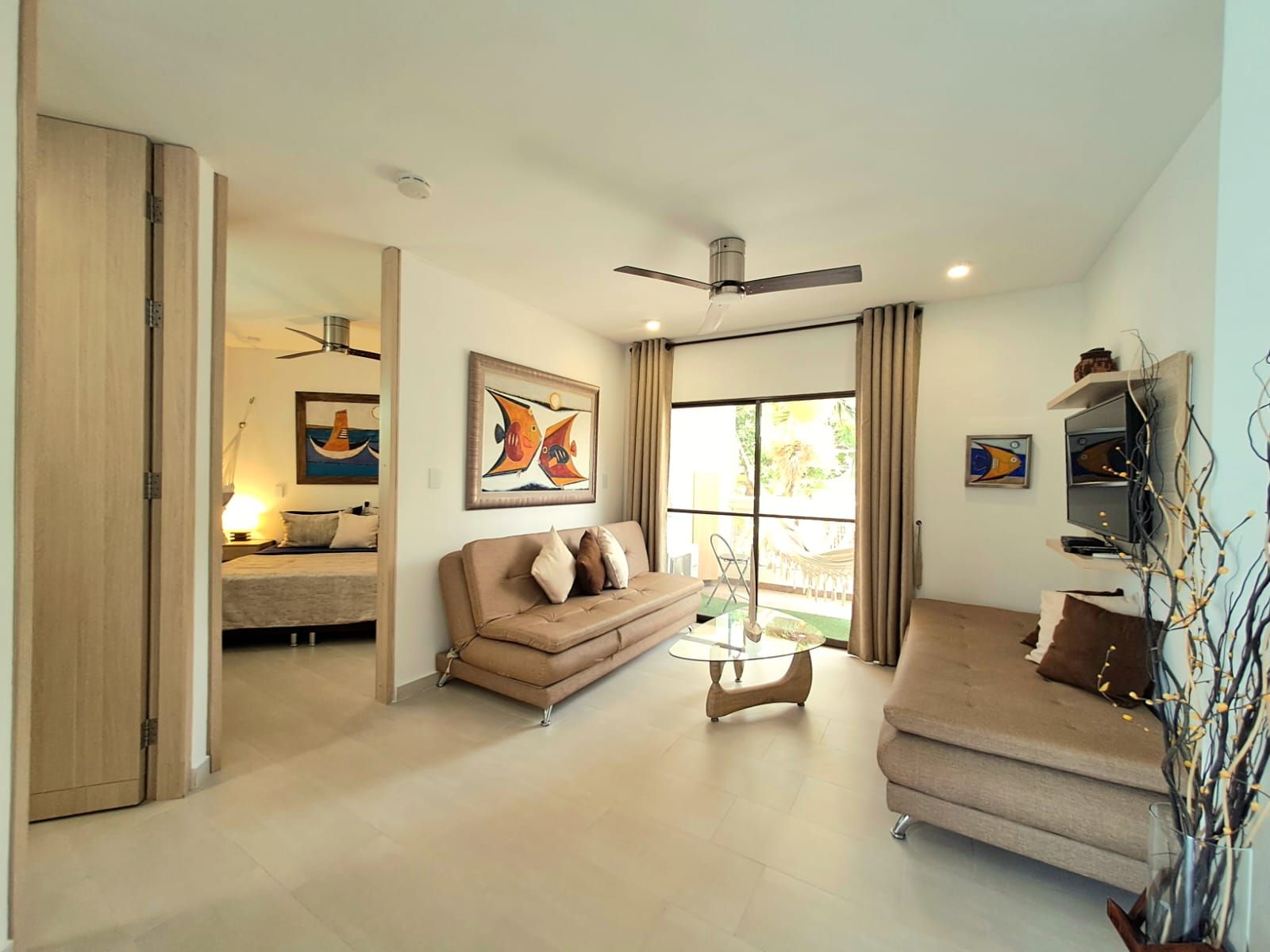 A modern living room with a sofa, a glass coffee table, and artwork on the walls.