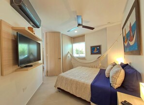 A bedroom with a bed, a TV, a ceiling fan, a hammock, and a painting. - Grob Home Studio Apartment, just a few steps from the beach and the Zazué Shopping Center (Santa Marta)