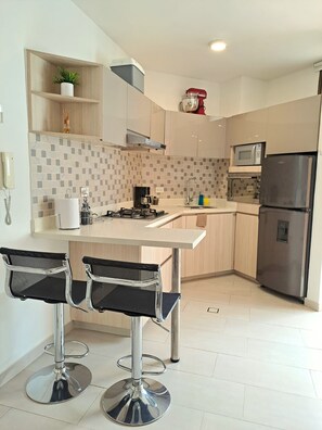 A modern kitchen with a central island, bar stools, a microwave, and a refrigerator. - Grob Home Studio Apartment, just a few steps from the beach and the Zazué Shopping Center (Santa Marta)