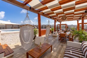 A rooftop terrace with a pool, wooden furniture, and hanging chairs. - Private Pool on Luxury Penthouse (Playa del Carmen)