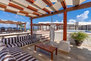 An outdoor seating area with a pool, wooden pergola, and a view of the ocean. - Private Pool on Luxury Penthouse (Playa del Carmen)