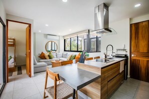 A modern kitchen with a central island, a dining area with a chair, and a built-in oven. - Steps From the Bucerias Beach With Rooftop Pool (Bucerías)
