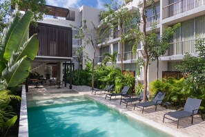 A hotel with a swimming pool, lounge chairs, and a covered outdoor seating area. - Private Pool With Great Comfort (Tulum)