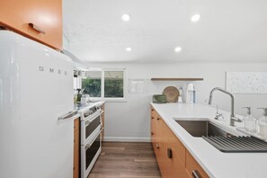 Eine moderne Küche mit weißen Schränken, einem Edelstahlkühlschrank und einem eingebauten Backofen.