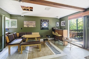 A room with a wooden table and benches, a dartboard, and a view of the outdoors. - The Après Chalet | Steps to Mount Snow w Fireplace (Dover)