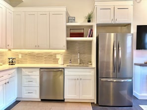 A modern kitchen with white cabinets, a stainless steel refrigerator, and a dishwasher.