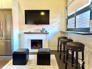 A modern kitchen with a built-in refrigerator, a fireplace, and a flat-screen TV mounted above it.