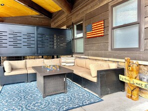 A cozy outdoor seating area with a fire feature, a flag, and a wooden sign indicating a lake.
