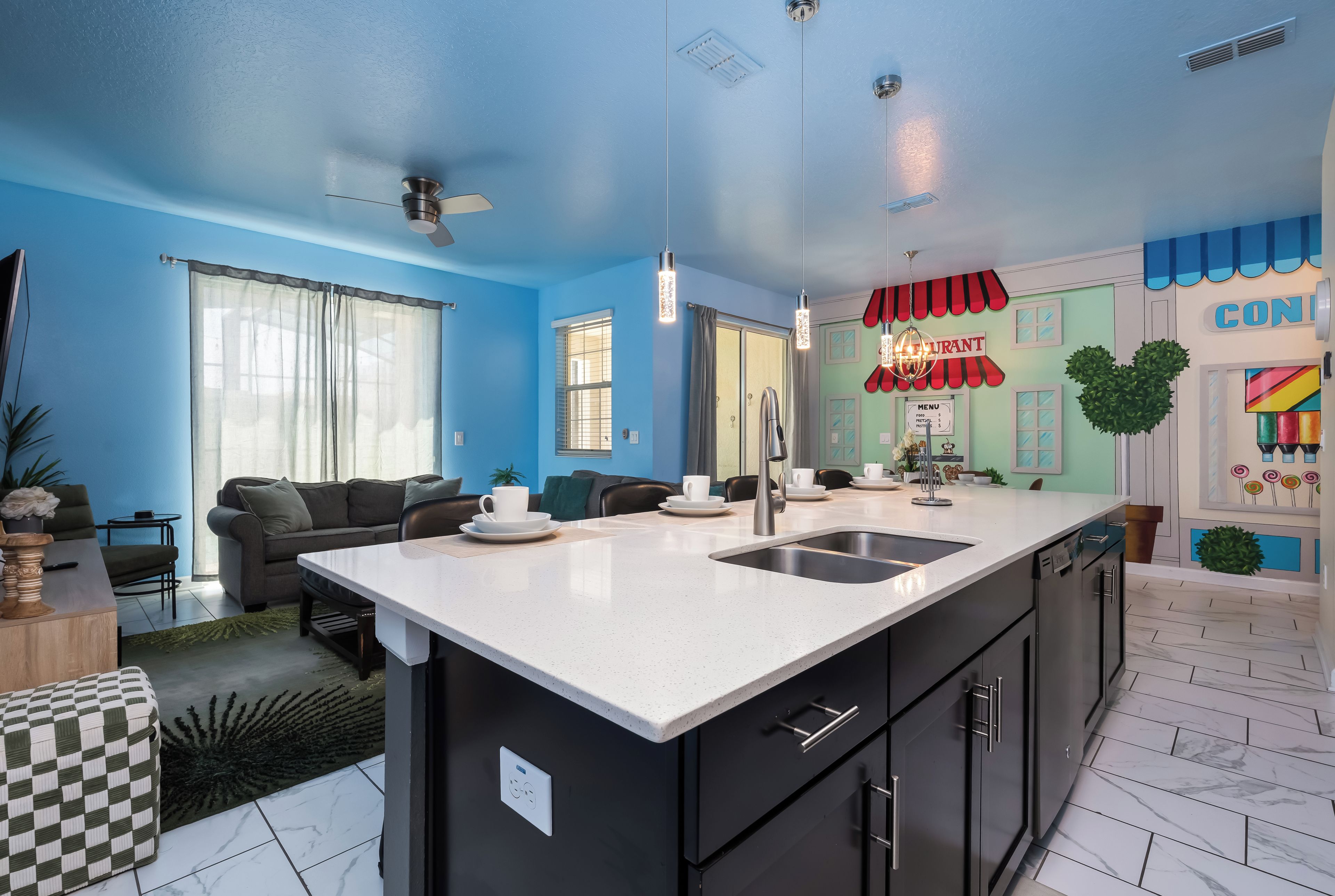 A modern kitchen with a large island, a dining area with a table and chairs, and a living room with a sofa and a coffee table.